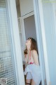 A woman in a red and white bikini standing in a doorway.