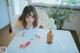 A woman sitting at a table with a glass of water and a strawberry.