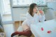 A woman sitting at a table eating a strawberry.