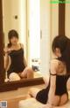 A woman sitting on a bed looking at herself in the mirror.