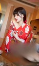 A woman in a red kimono sitting on a table.