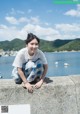 A woman sitting on the edge of a concrete wall by the water.