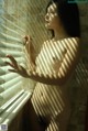 A naked woman standing in front of a window.