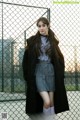 A woman standing in front of a chain link fence.