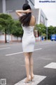 A woman in a white dress is standing on the street.