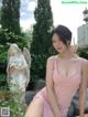 A woman in a pink dress posing in front of a statue.