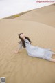 A woman laying on top of a sand dune.