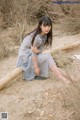 A woman sitting on a log in the sand.