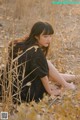 A woman sitting in a field of dry grass.