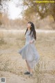 A woman in a gray dress standing in a field.