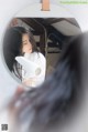 A woman blow drying her hair in front of a mirror.