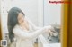 A woman in a white shirt is preparing food in a kitchen.