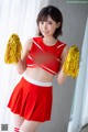 A woman in a red and white cheerleading uniform holding pom poms.