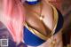 A woman with pink hair wearing a blue and gold bikini.