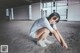 A woman crouching down on the ground in an empty room.