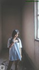 A woman standing in an empty room next to a window.