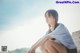 A woman sitting on the edge of a concrete wall.