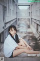 A woman sitting on the ground in an abandoned building.