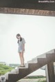 A woman standing on a set of stairs near a body of water.