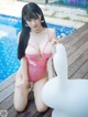 A woman in a pink lingerie sitting next to a pool.