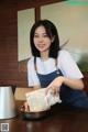 A woman in a white shirt and blue overalls holding a bag of food.