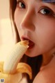 A woman eating a banana with her mouth open.