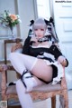 A woman in a maid outfit sitting on a chair.