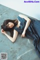 A woman in a blue dress laying on the ground.