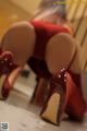 A woman in a red lingerie and high heels is bending over.