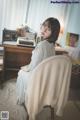 A woman sitting on a chair in front of a typewriter.