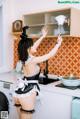 A woman in a maid outfit is cleaning a kitchen.