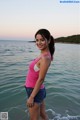 A woman in a pink tank top standing in the ocean.