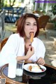 A woman sitting at a table eating a hot dog.