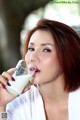 A woman drinking a glass of milk from a glass.