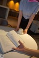 A woman sitting at a table with a cup of coffee and a book.