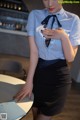 A woman in a blue shirt and black skirt holding a cell phone.