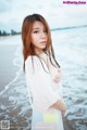 A woman standing on a beach next to the ocean.