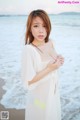 A woman in a white dress standing on a beach.