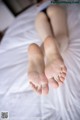 A woman laying on top of a bed with her feet up.