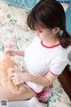 A woman sitting on a bed holding a teddy bear.