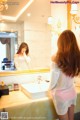 A woman standing in front of a mirror in a bathroom.