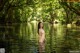 A naked woman standing in the middle of a river.