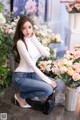 A woman sitting on the ground next to a bunch of flowers.