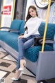 A woman sitting on a blue couch in a train.