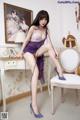 A woman in a purple lingerie sitting on a chair.