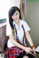 A woman in a school uniform sitting on a chair.