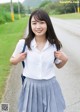 A woman in a white shirt and gray skirt posing for a picture.