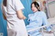 A woman in a hospital room with a nurse standing next to her.