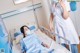 A woman in a hospital bed with a nurse standing next to her.