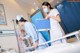 Two nurses in a hospital room with a patient in a bed.